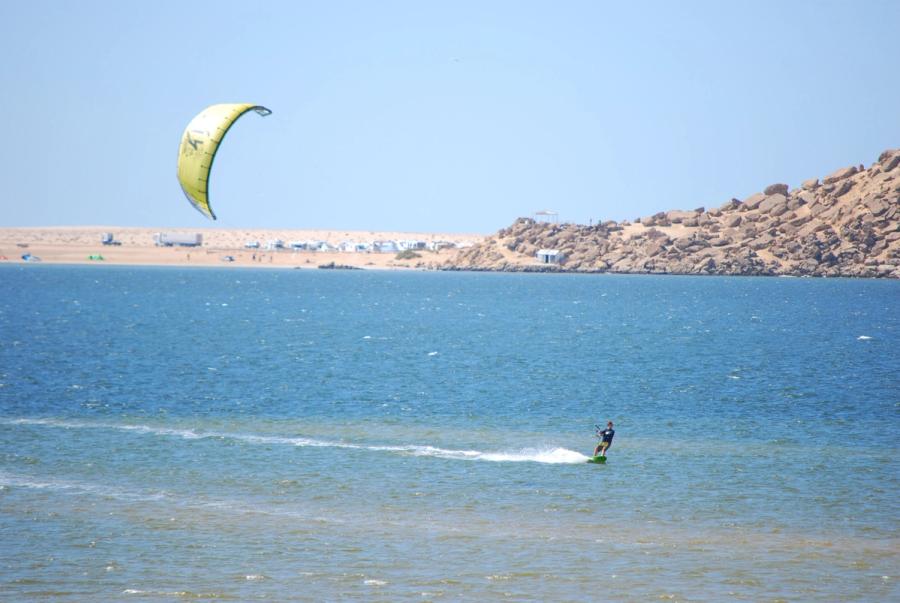 A kitesurfer on the Dakhla lagoon with dunes on the far shore