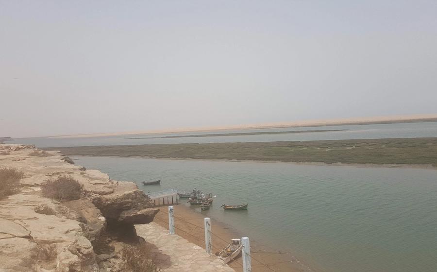 Fishing boats moored in the Khnifiss Lagoon below a low limestone cliff