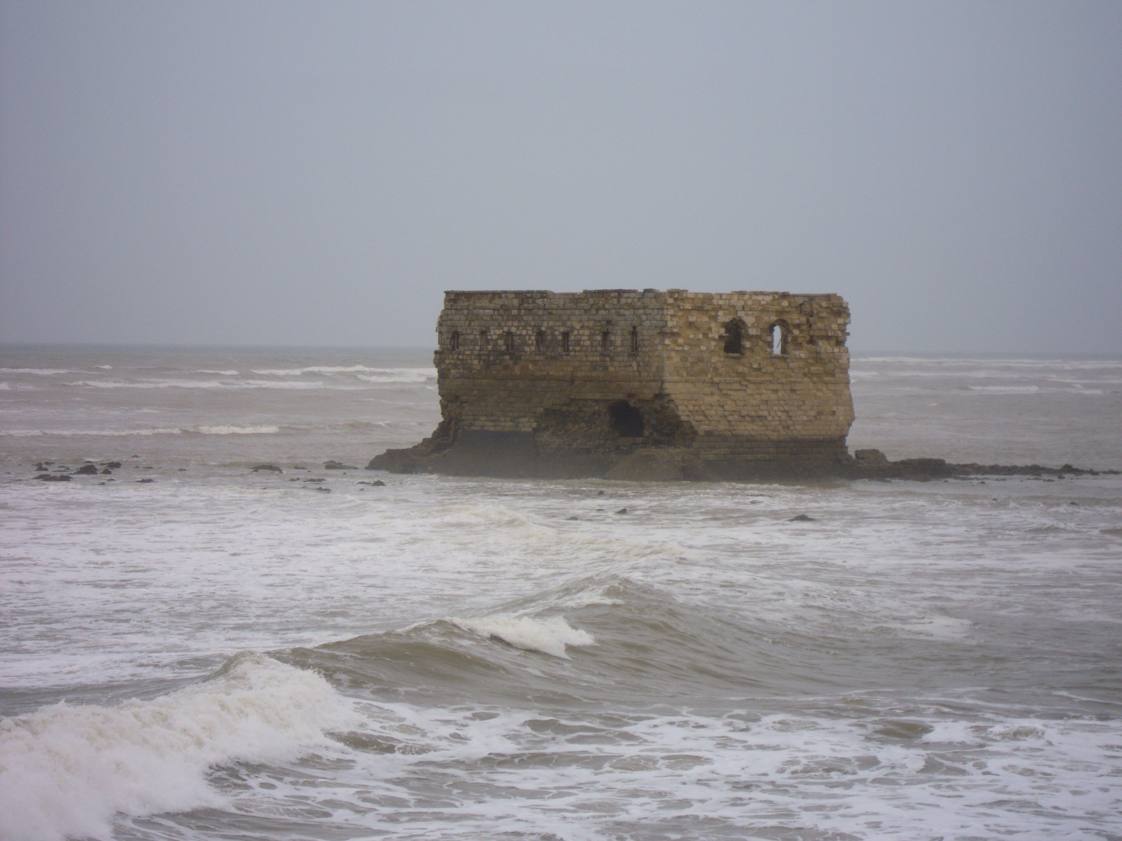 Waves breaking around Casa Mar on its rocky islet off Tarfaya
