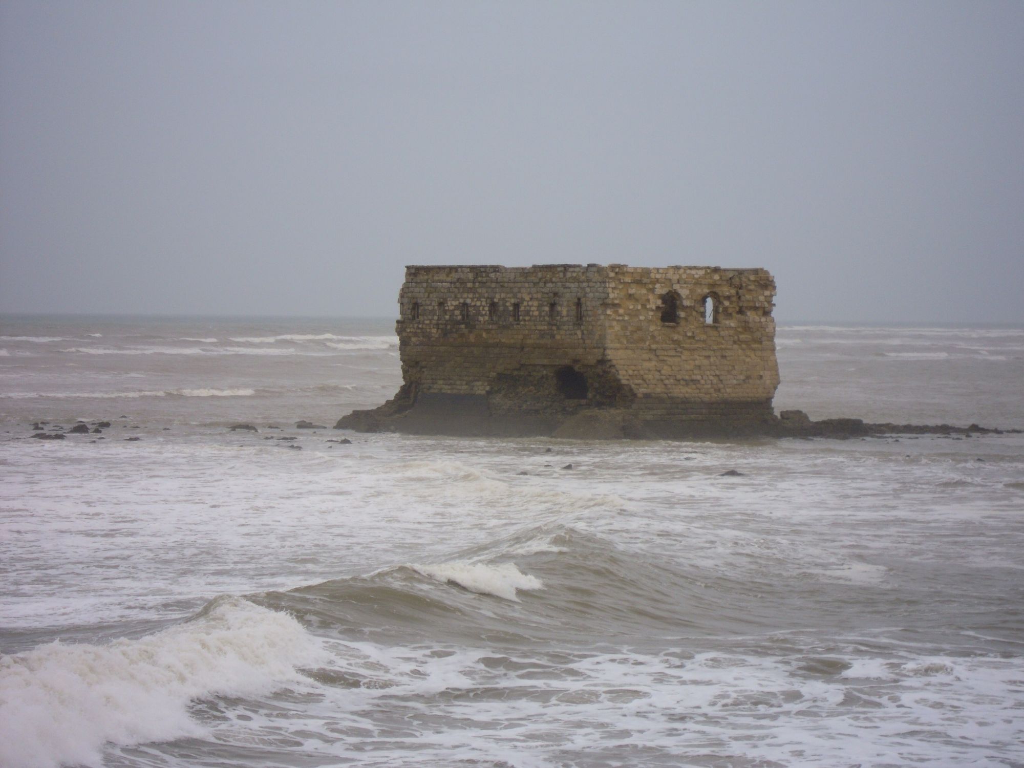 Waves breaking around Casa Mar on its rocky islet off Tarfaya