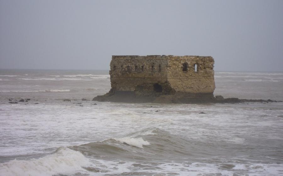 Waves breaking around Casa Mar on its rocky islet off Tarfaya