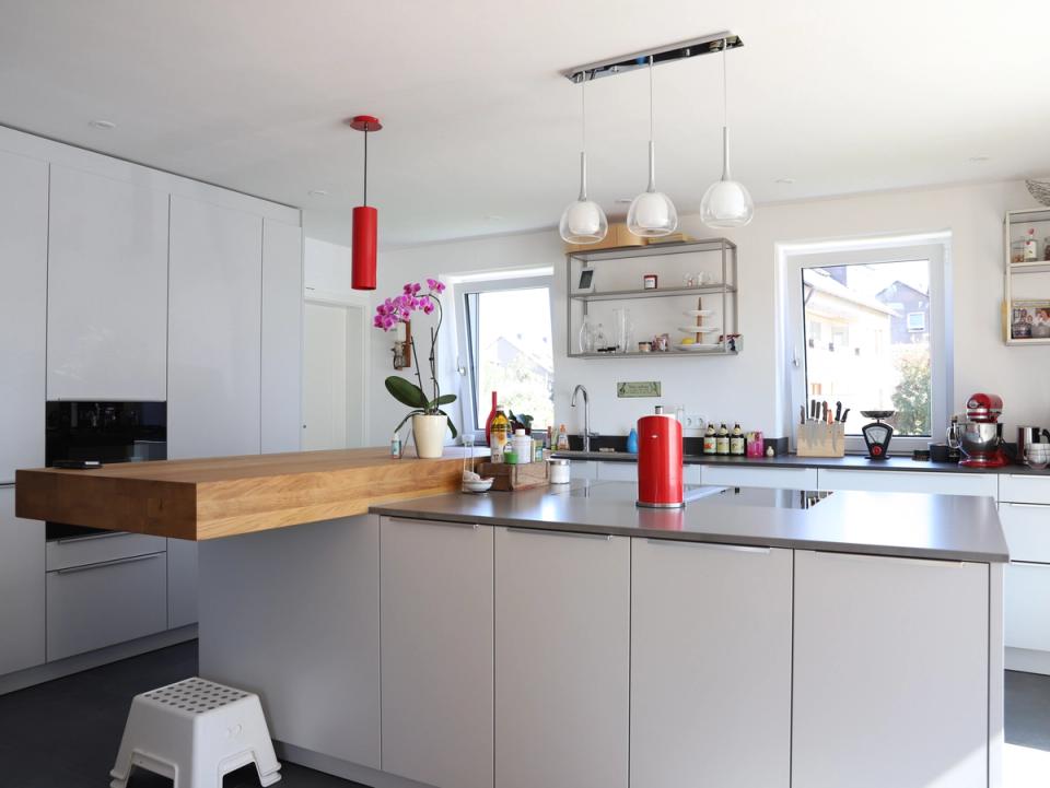 Moderne Küche mit grauen Fronten, Holztheke und roten Akzenten