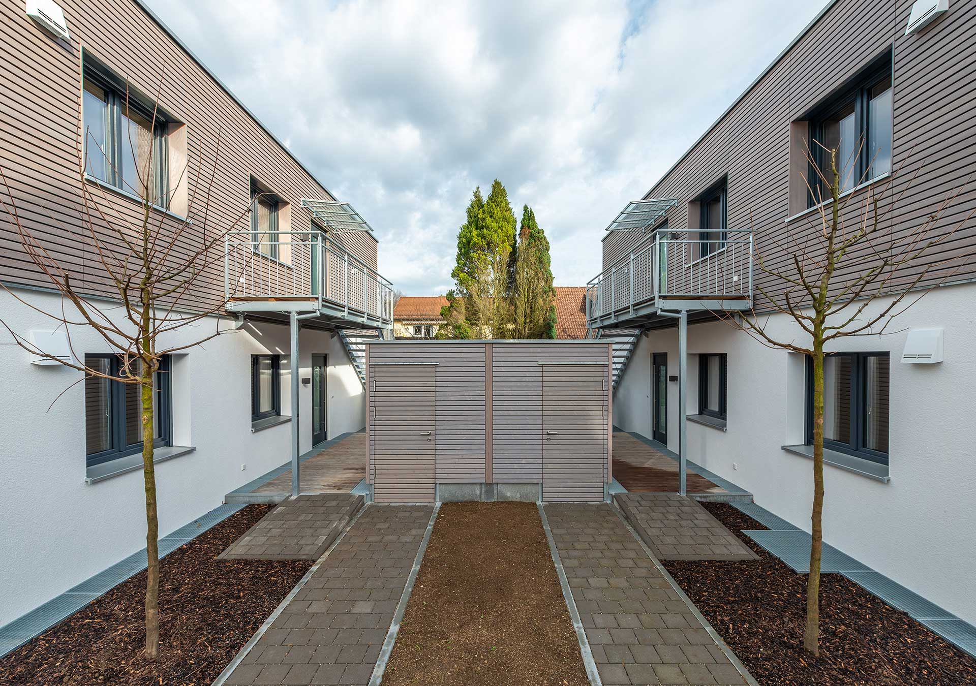 Innenhof zwischen zwei Modulbauten mit Balkonen und Jungbäumen
