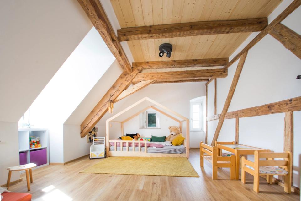 Kinderzimmer im Dachgeschoss mit sichtbaren Holzbalken und Hausbett