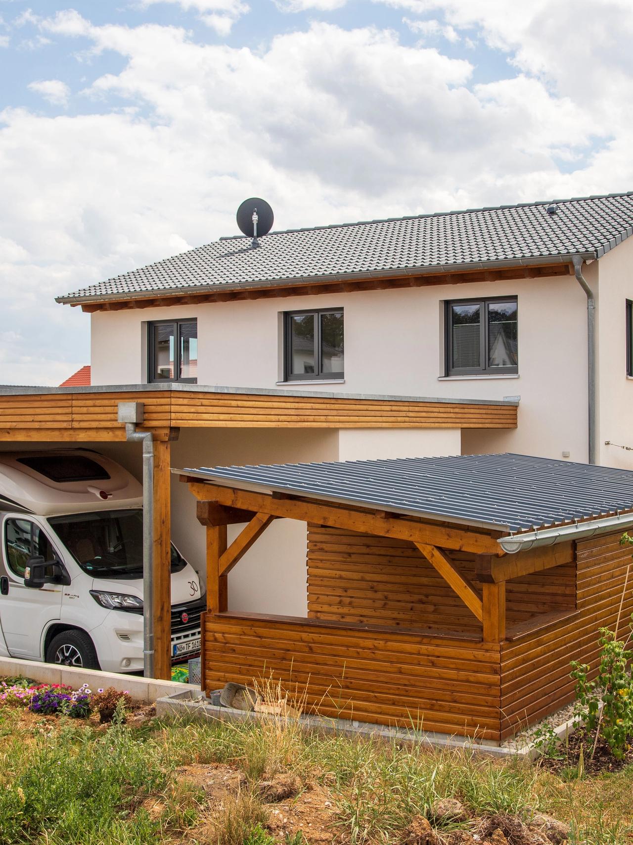 Neubau mit Satteldach, Carport und Holzgartenhaus im Sommer