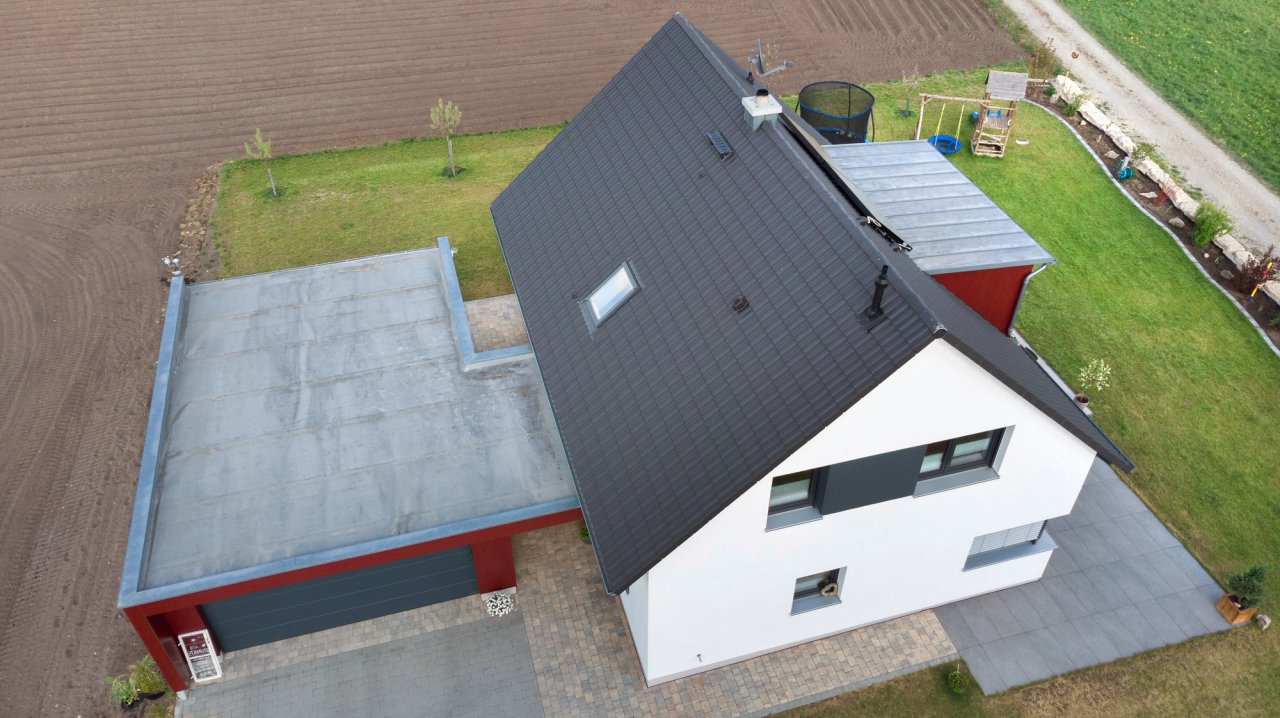 Satteldach mit Gaube und Flachdachgarage von oben, dahinter Feld und Wiese