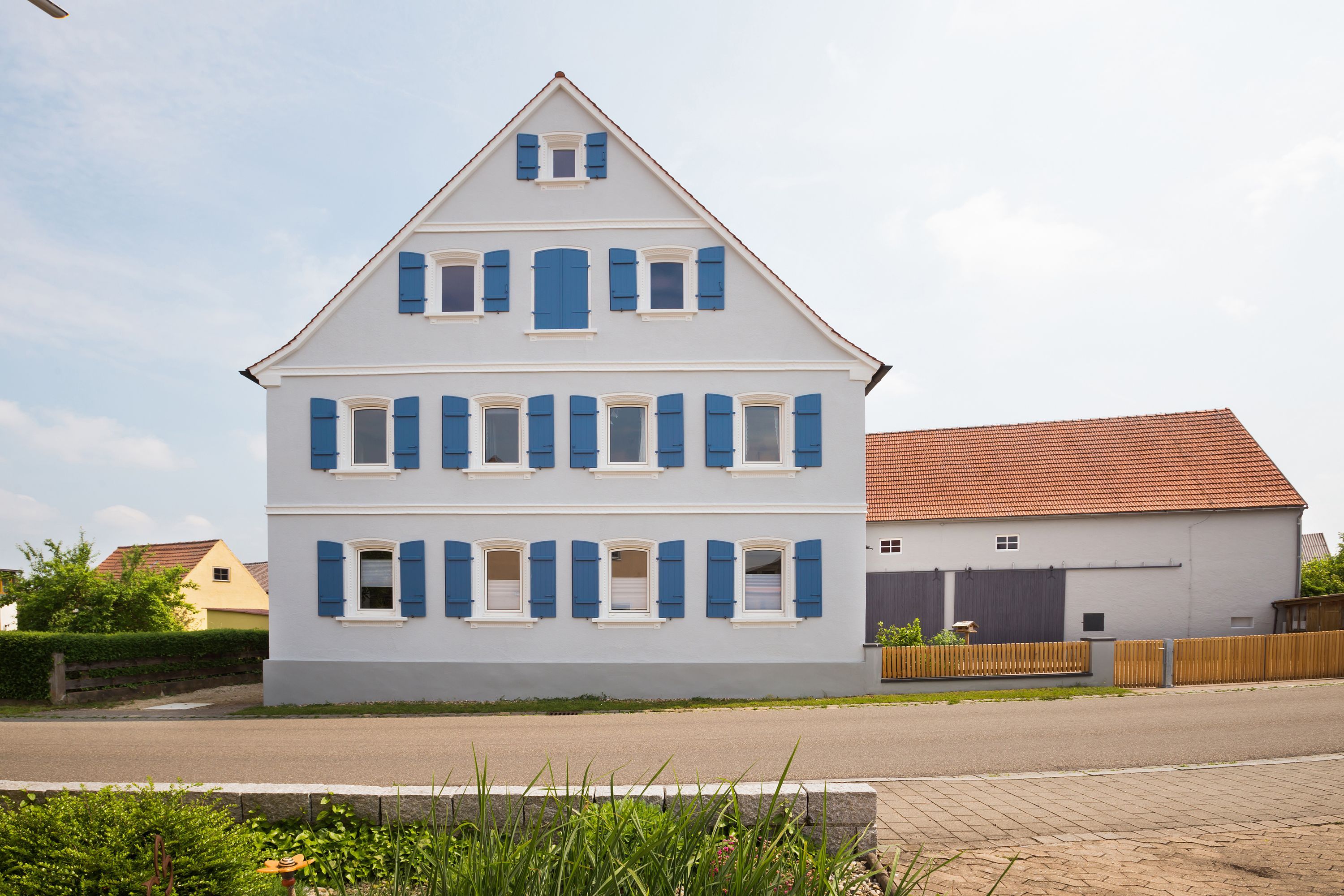 Sanierte Giebelfassade mit blauen Fensterläden