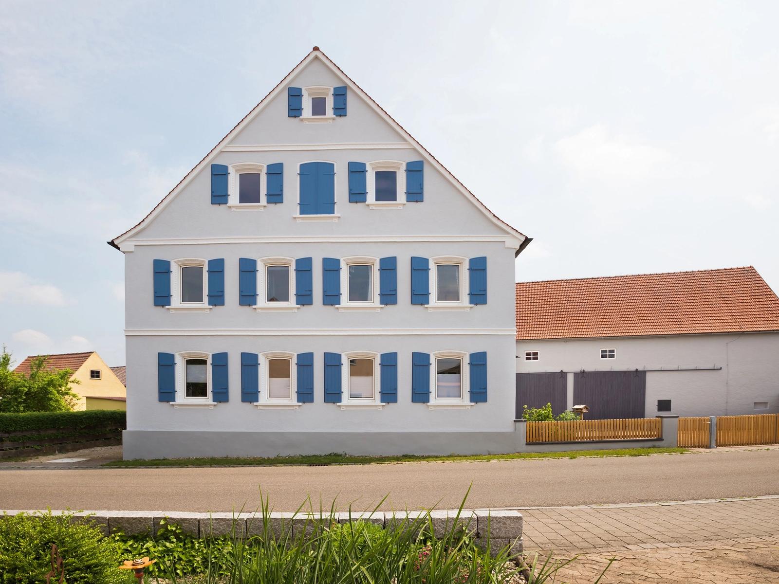 Sanierte Giebelfassade mit blauen Fensterläden