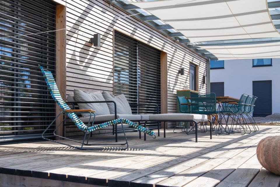 Überdachte Holzterrasse mit Loungemöbeln und Sonnensegeln