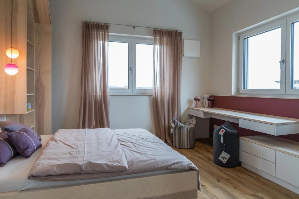 Schlafzimmer mit Doppelbett, Schreibtisch und rosa Vorhängen