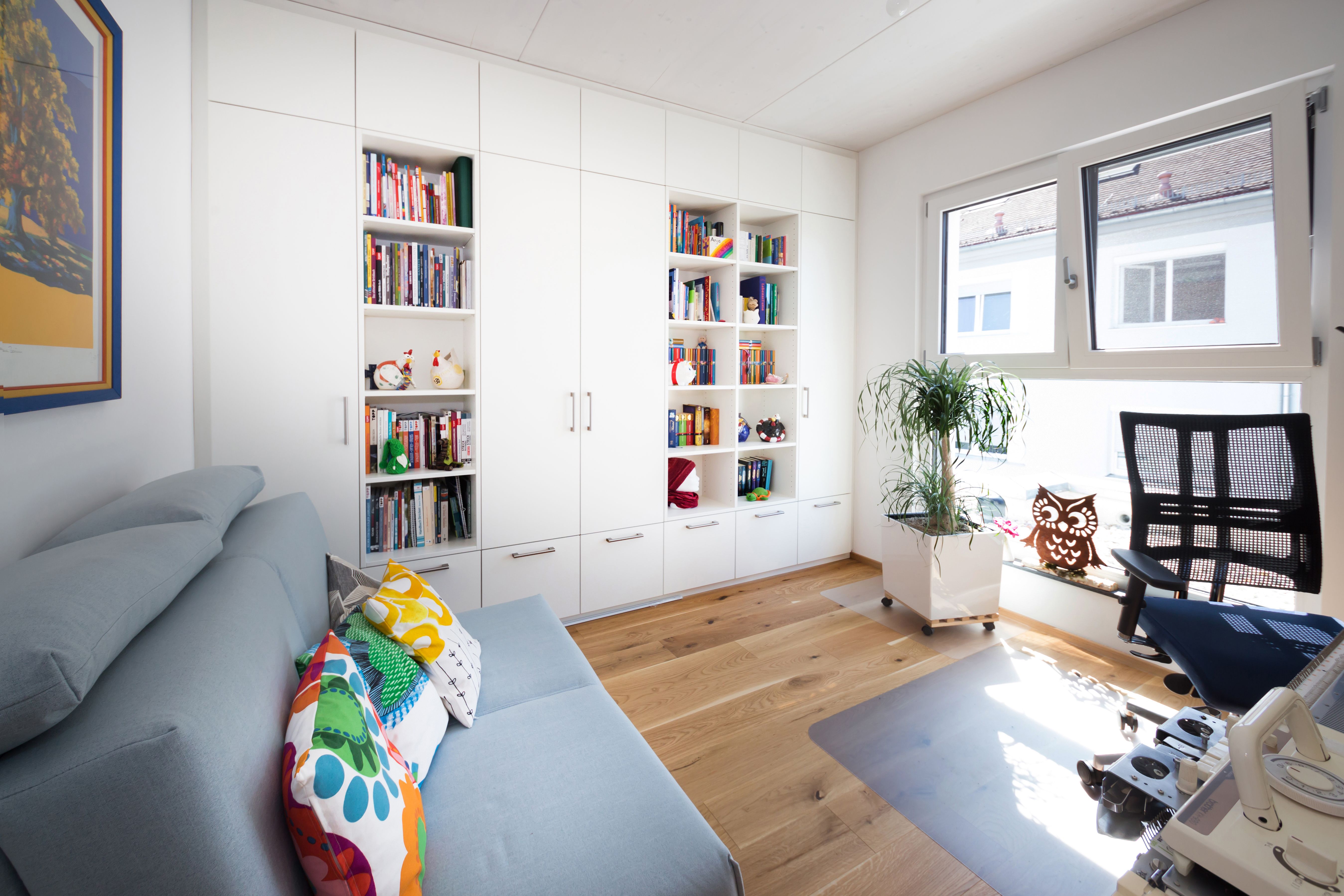Arbeitszimmer mit raumhohem weißem Einbauschrank und offenen Regalen