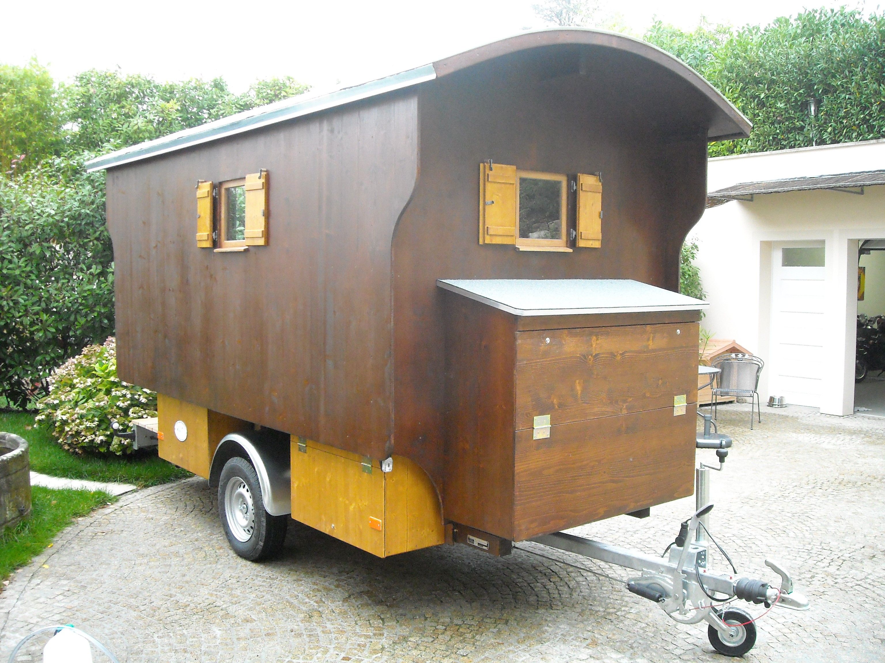 Dunkelbrauner Jagdwagen mit gewölbtem Dach, gelben Fensterläden und Staukasten an der Deichsel