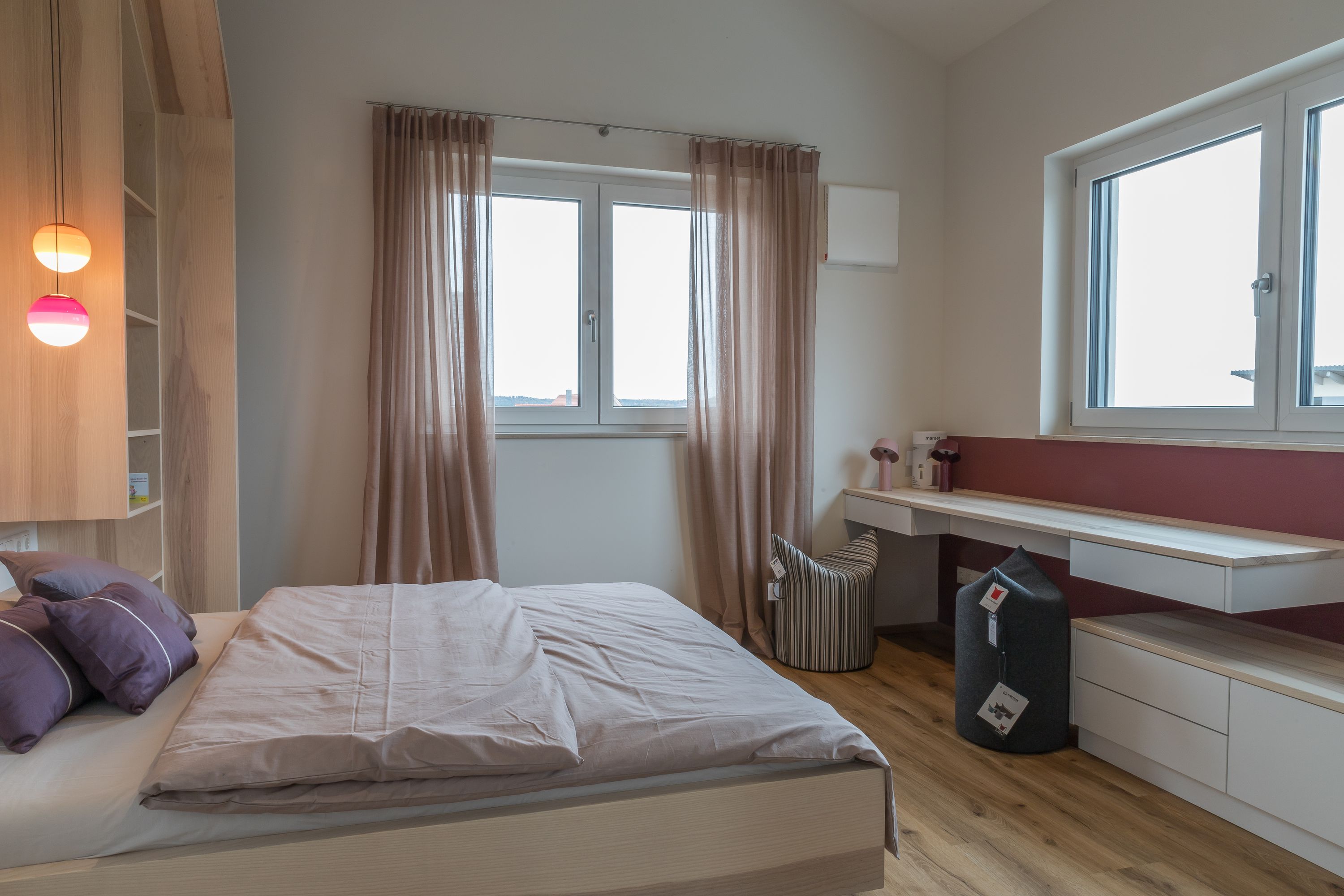 Helles Schlafzimmer mit Doppelbett und Fenstern über Eck