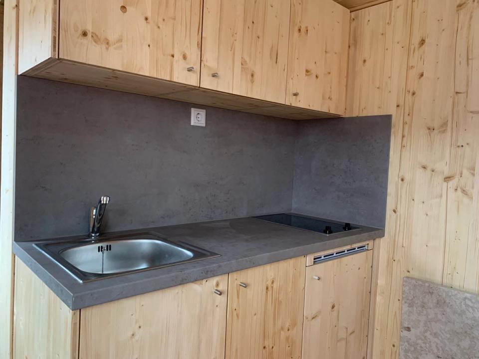 Küchenzeile mit Spüle, Kochfeld und Schränken aus hellem Holz im Waldkindergartenwagen