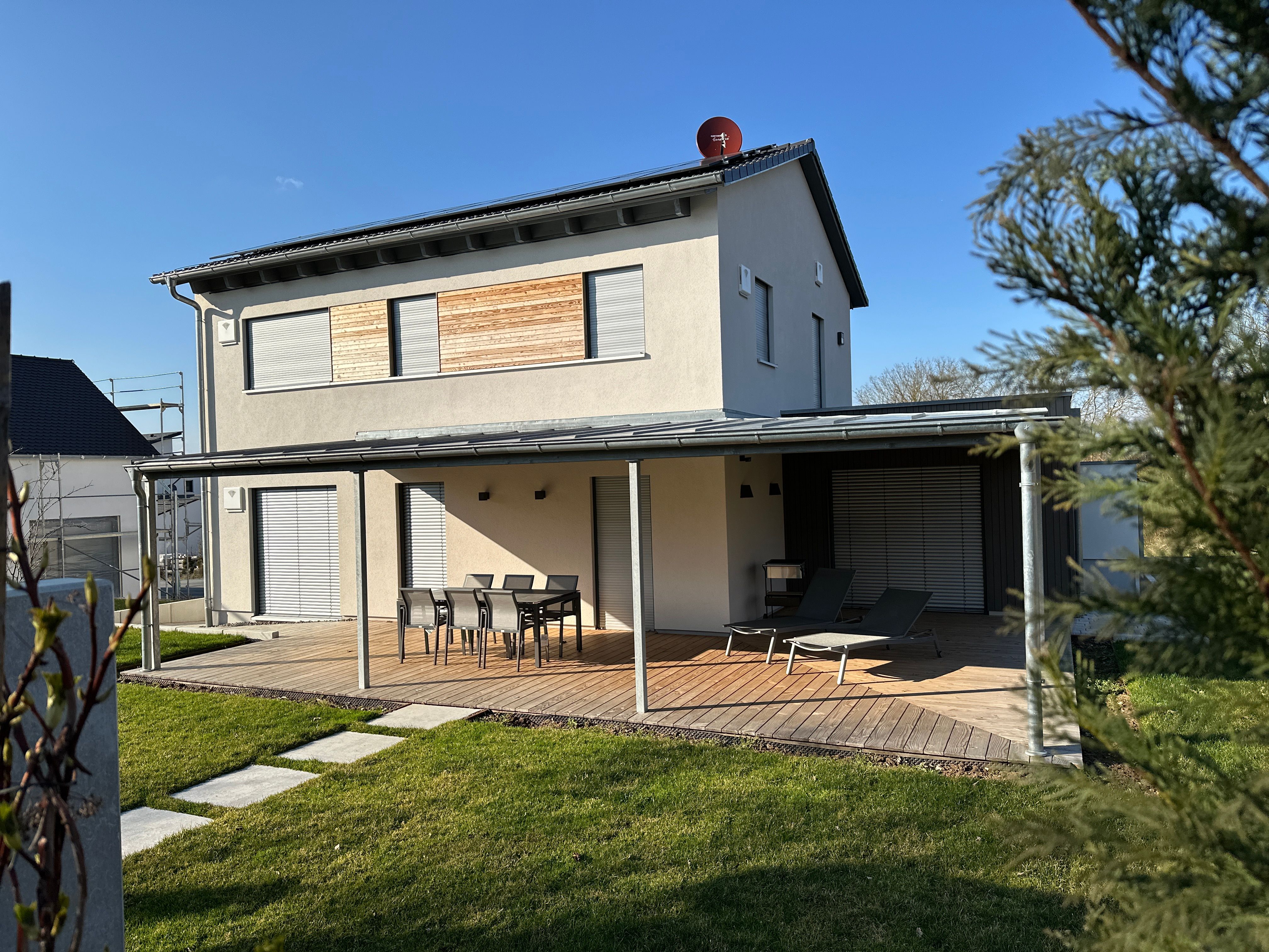 Hausrückseite des Musterhauses mit Holzterrasse im Abendlicht