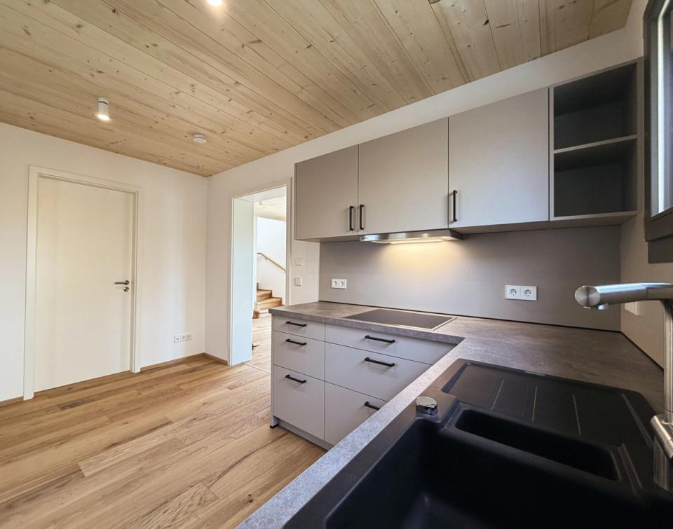 Küche mit grauen Fronten, Holzdecke und Eichenparkett