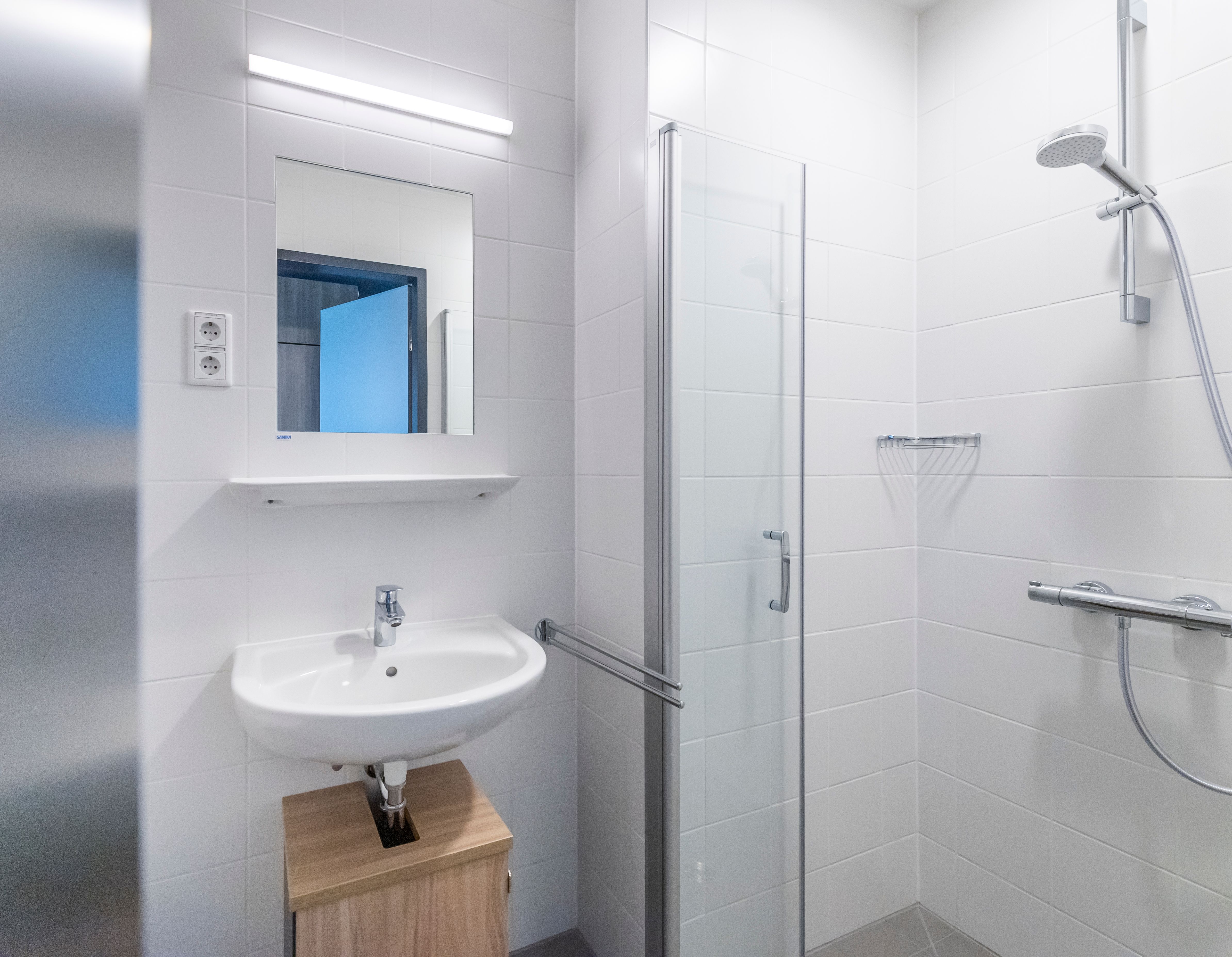 Weiß gefliestes Bad mit Dusche im Unterkunftsgebäude
