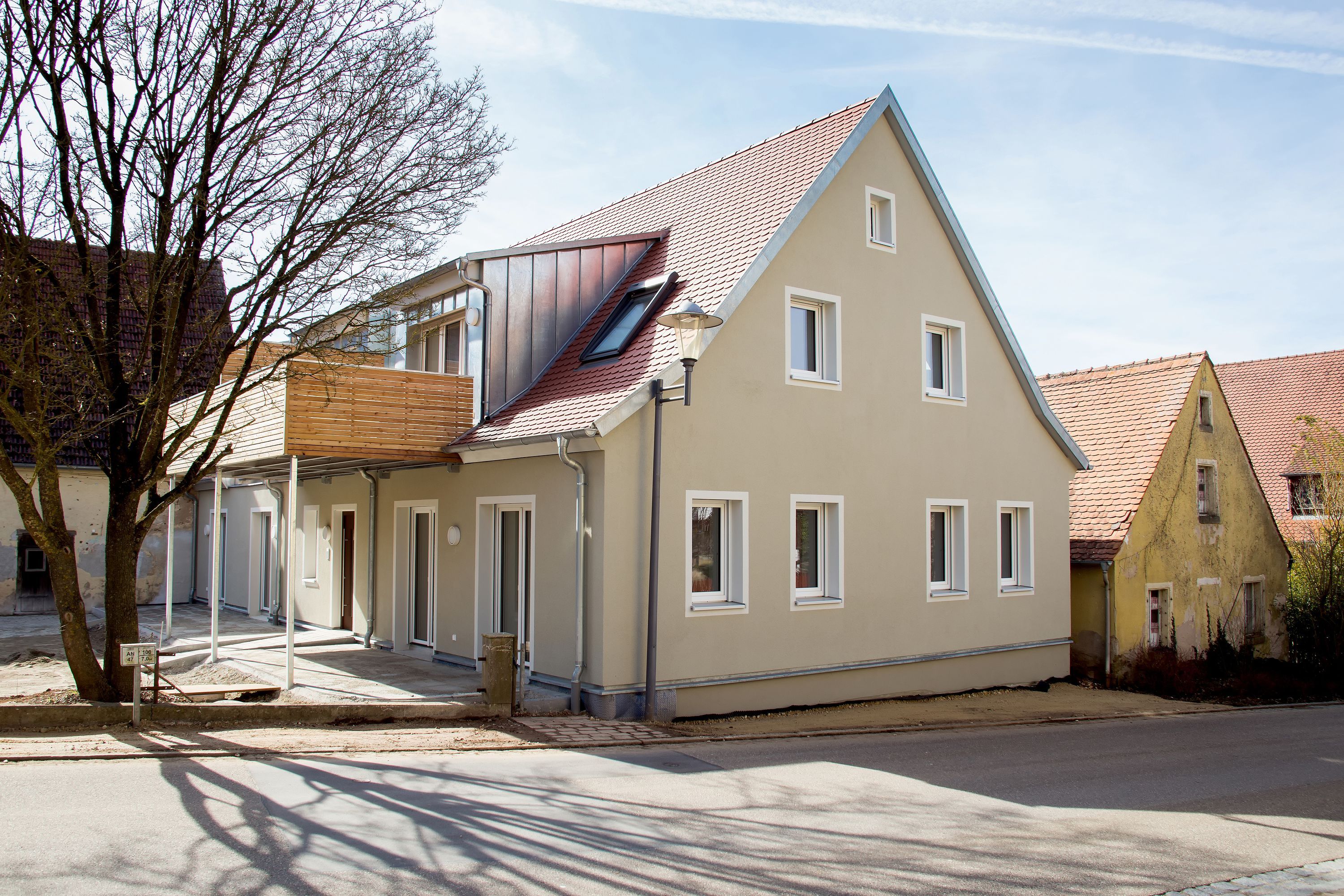 Saniertes Wohnhaus mit rotem Ziegeldach und Holzbalkon