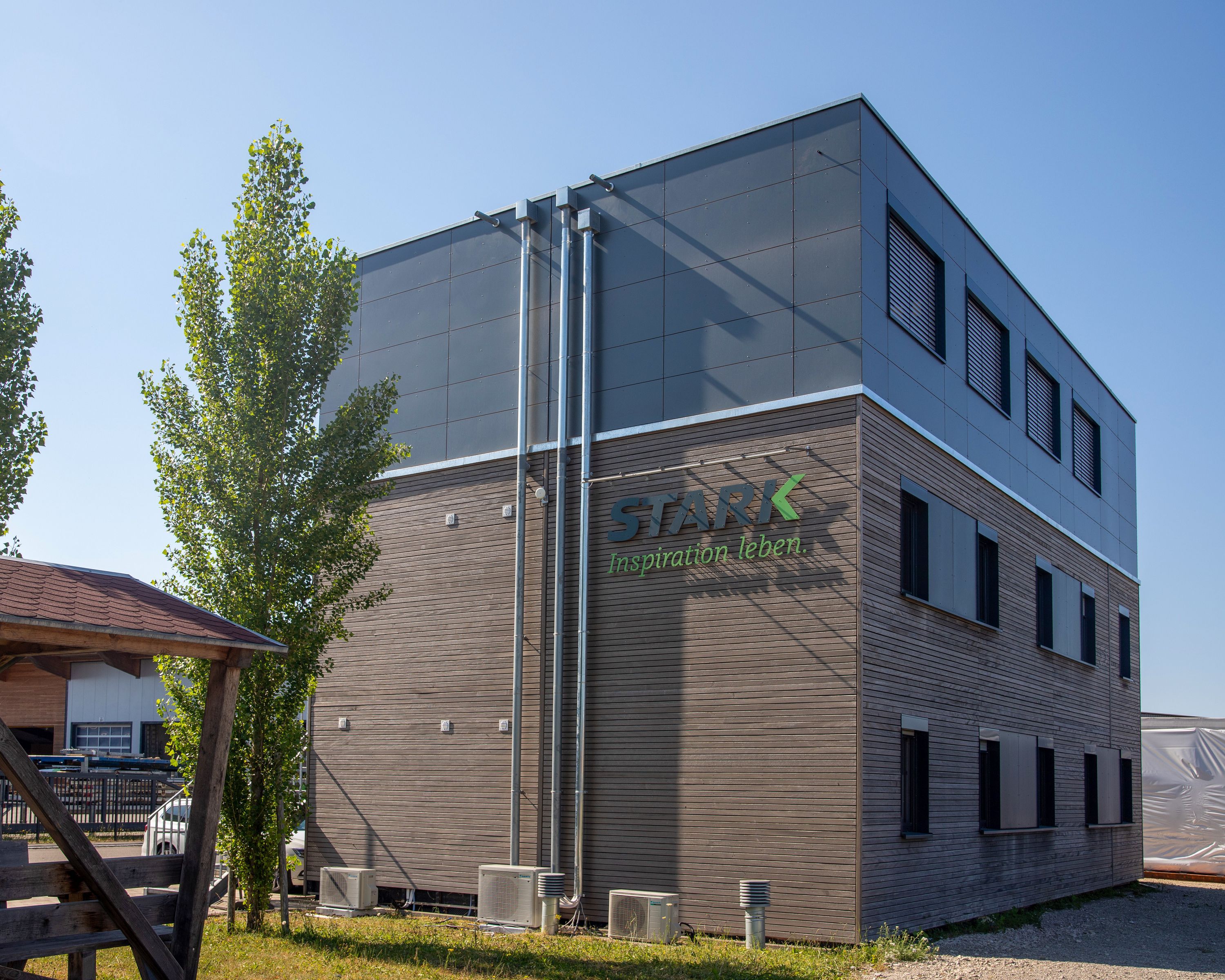 Aufgestocktes Bürogebäude der Zimmerei Stark mit Holzfassade und dunklem Plattengeschoss
