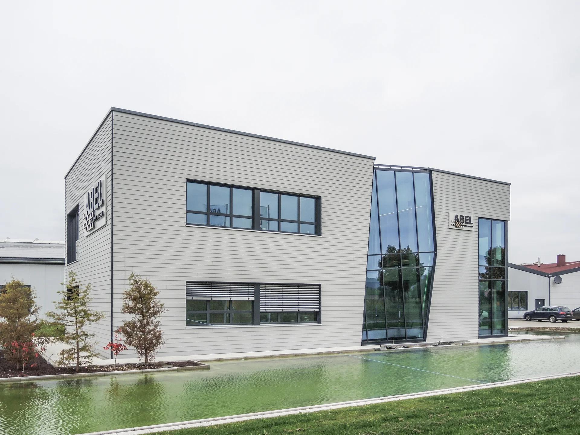 Bürogebäude Westheim mit Holzfassade, gespiegelt im Wasserbecken