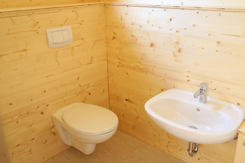 WC-Raum im Waldkindergartenwagen mit Toilette und Waschbecken vor Wänden aus Holz