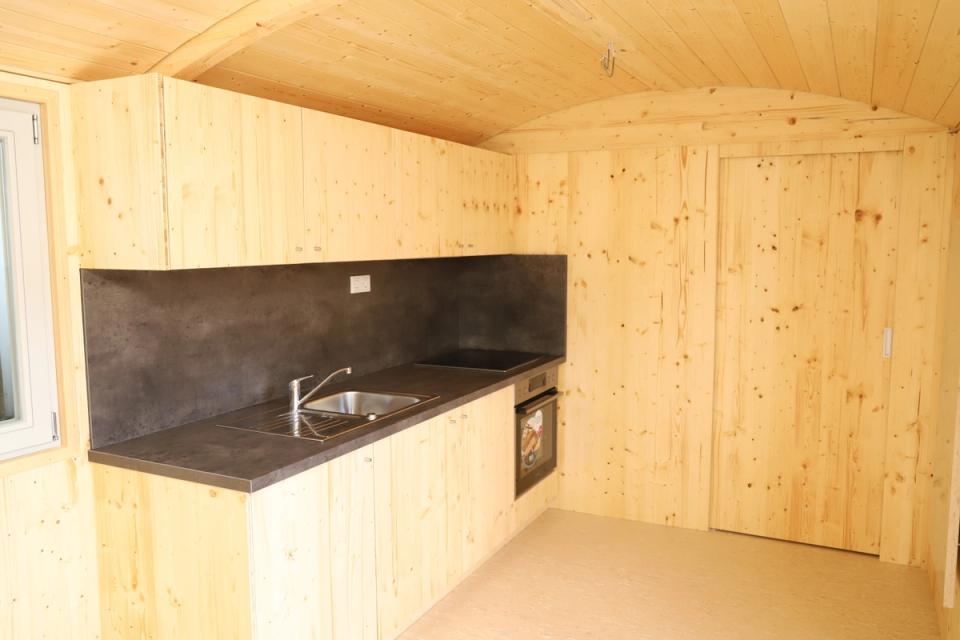 Küchenzeile mit Spüle, Kochfeld und Backofen in einem Waldkindergartenwagen aus Fichtenholz
