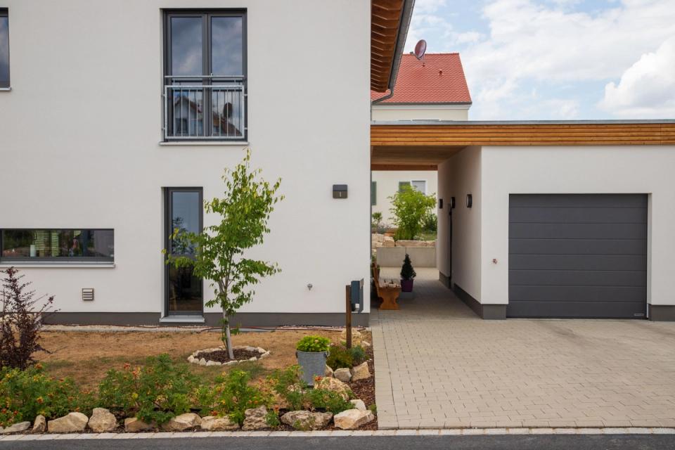 Eingangsbereich mit jungem Baum, Garage und überdachtem Durchgang