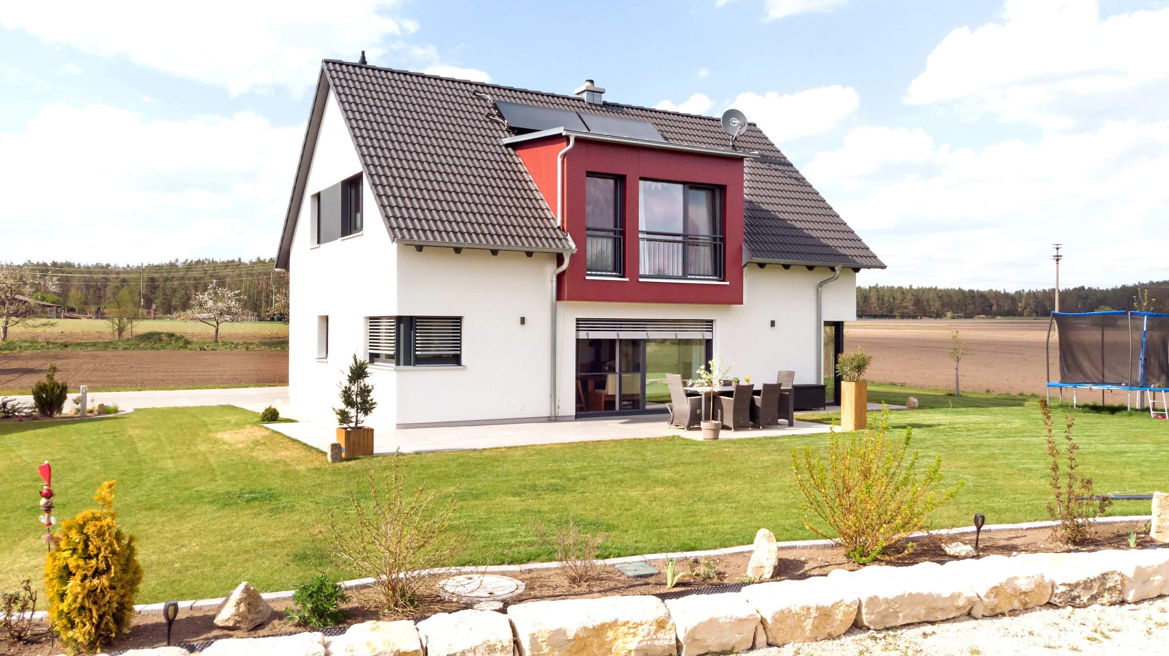 Terrasse und Garten mit Trampolin vor freier Feldlage