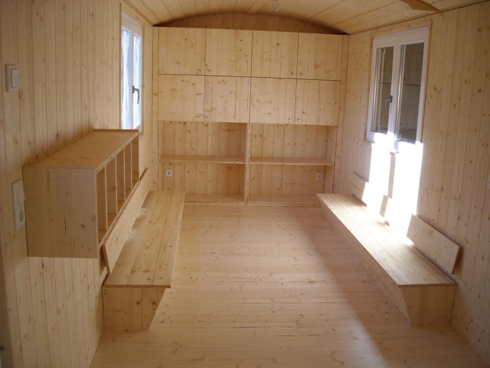 Innenraum mit Bänken, Garderobenfächern und Schrankwand aus hellem Holz
