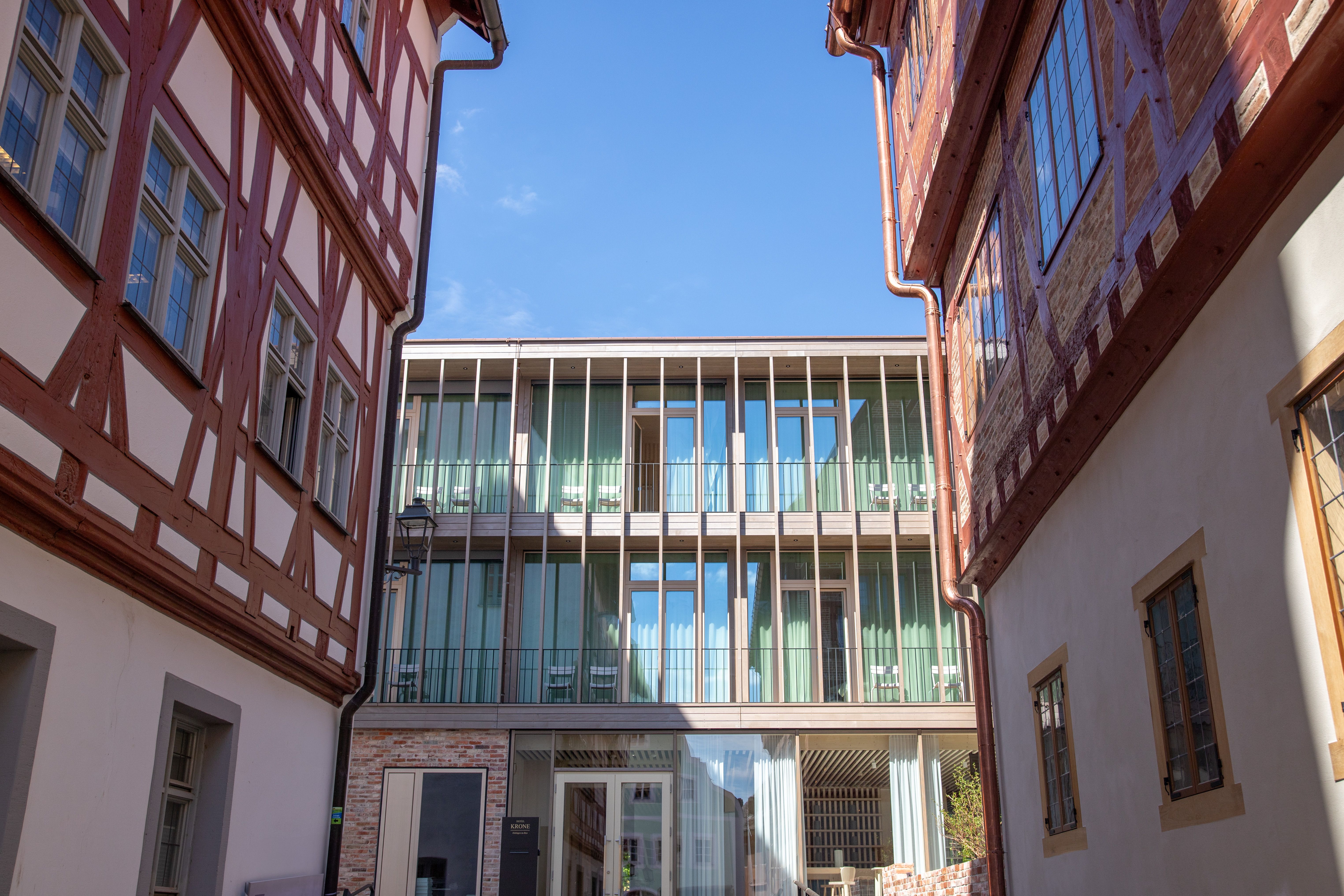 Hotelneubau mit Holzlamellen und Balkonen zwischen zwei Fachwerkhäusern
