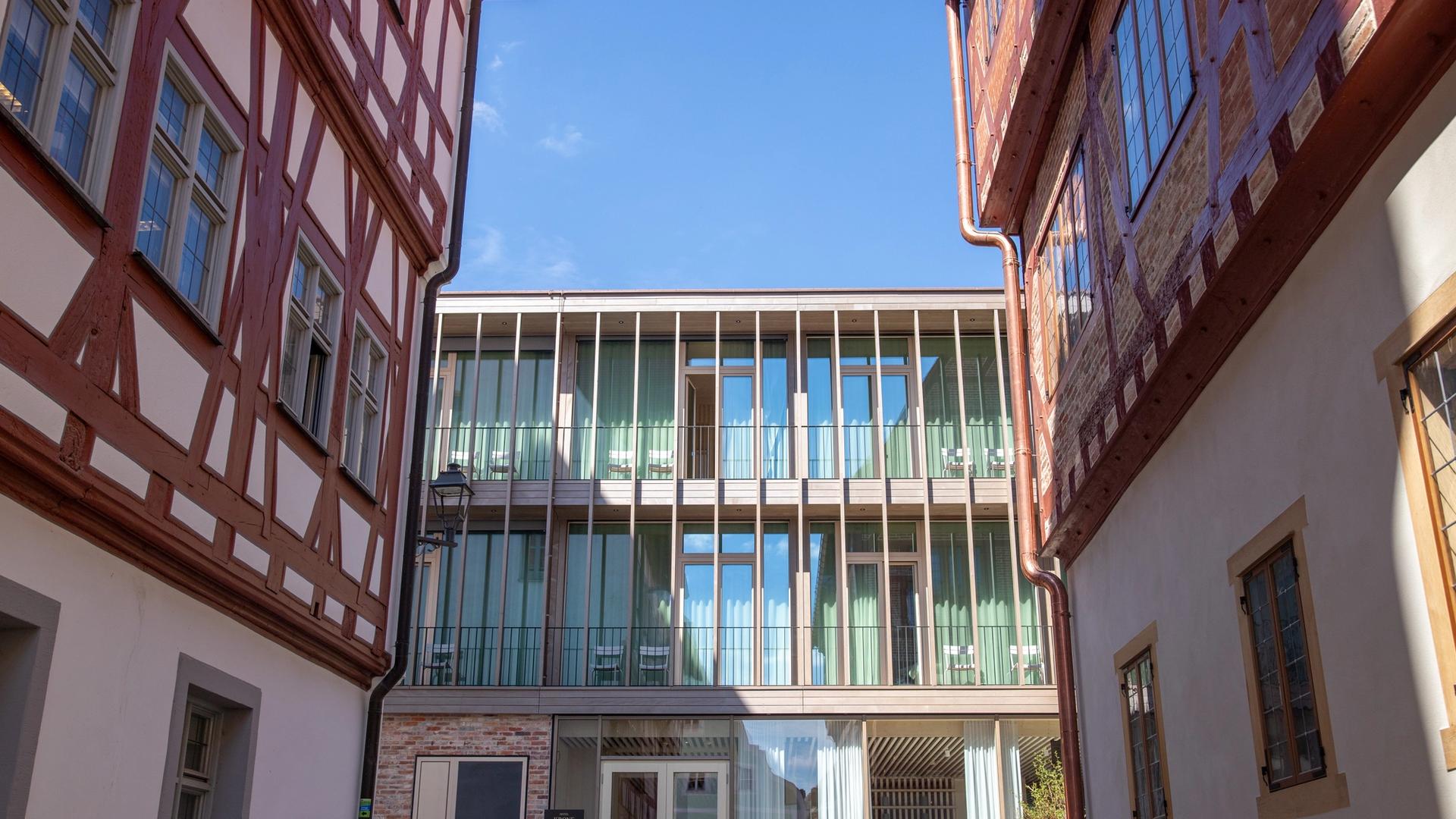 Hotelneubau mit Holzlamellen und Balkonen zwischen zwei Fachwerkhäusern