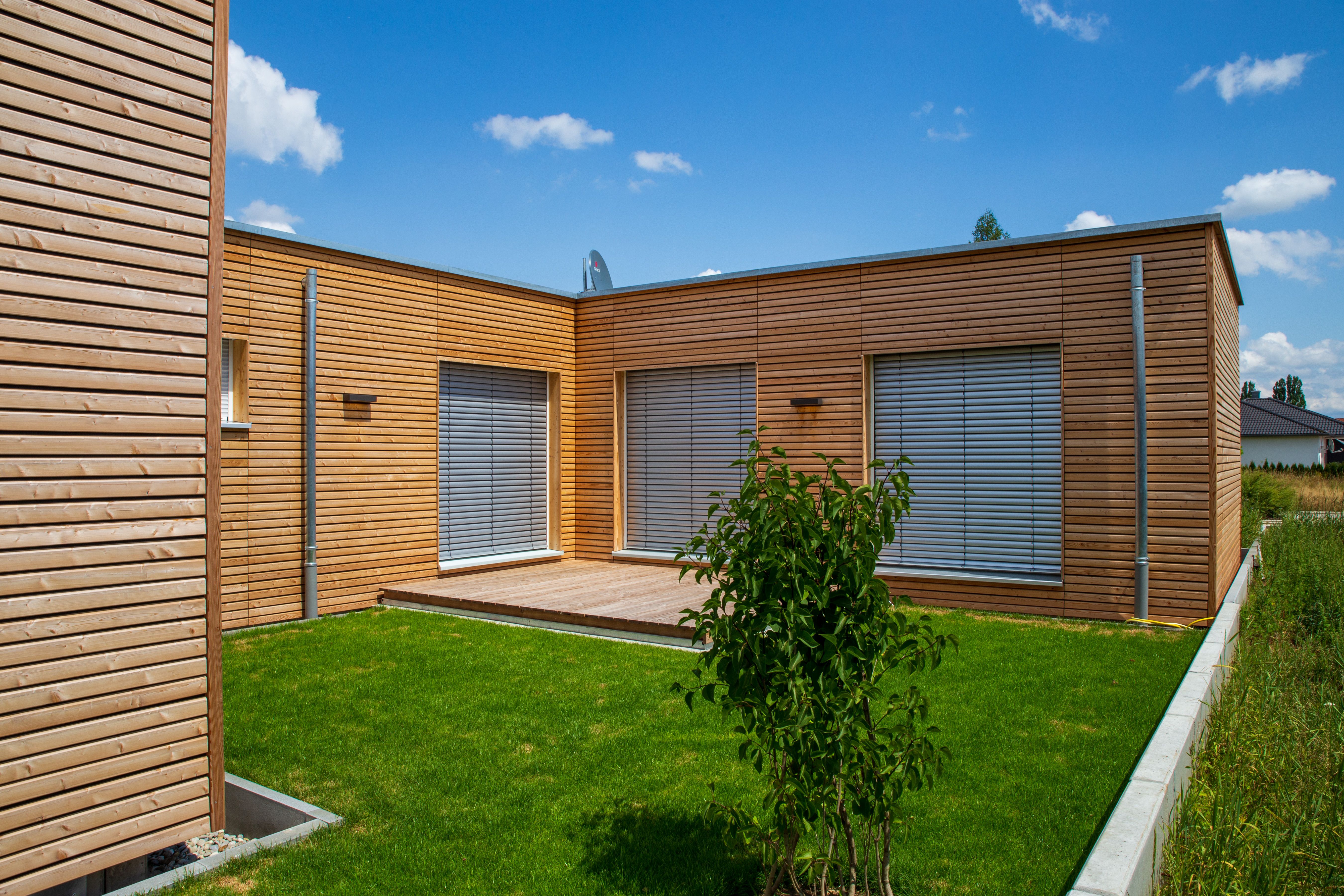 Atriumhaus mit Lärchenholzfassade, Innenhof mit Rasen und Holzterrasse