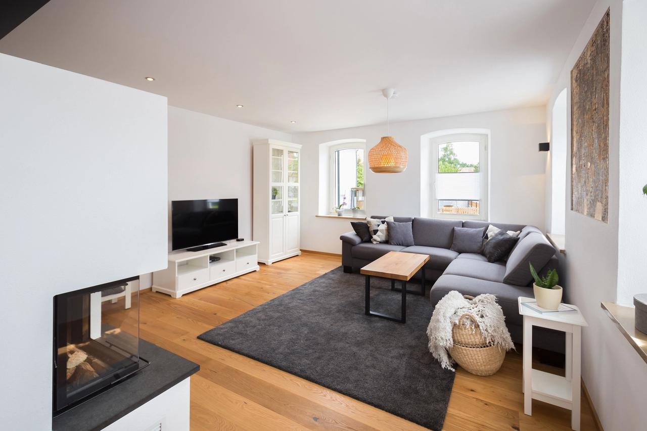 Wohnzimmer mit Kamin, grauem Sofa und erhöhter Sitzebene