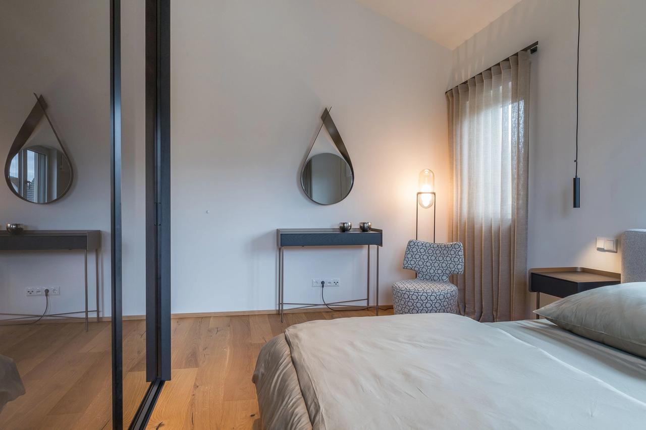 Kleiderschrank mit dunkler Glas-Schiebetür und Spiegelung des Bettes