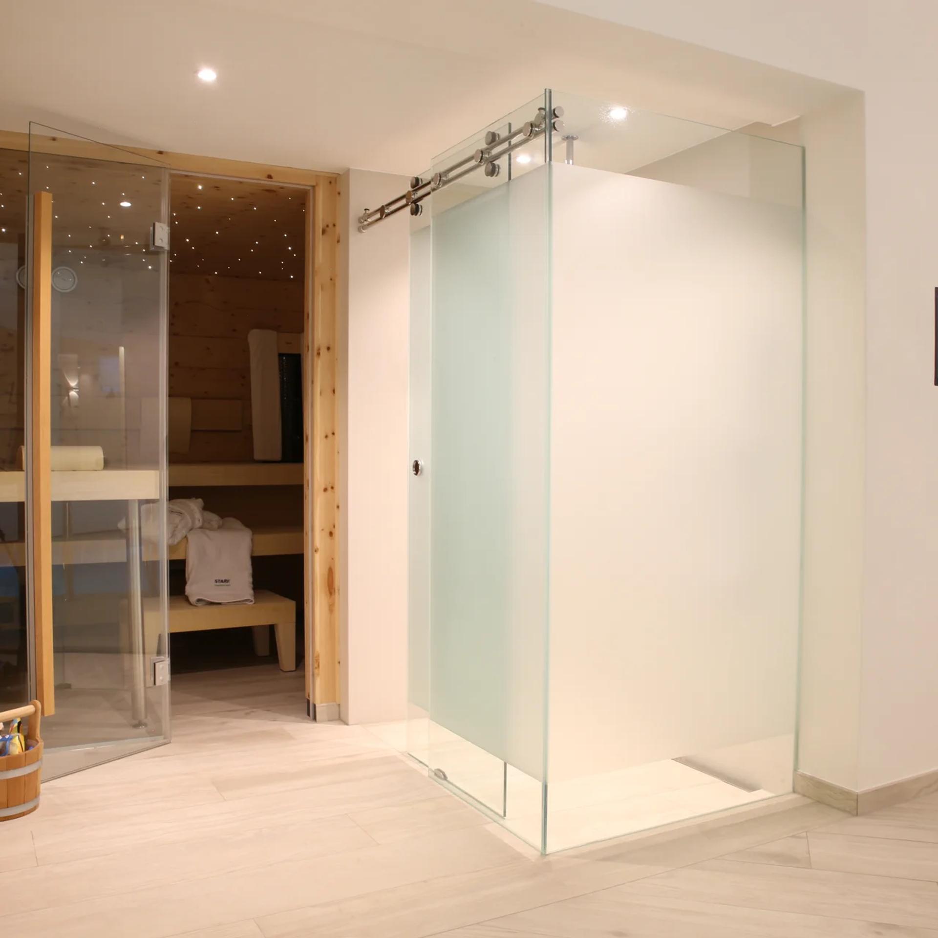 Einbausauna mit Glastür und Sternenhimmel, Dusche im Hintergrund — Zimmerei Stark