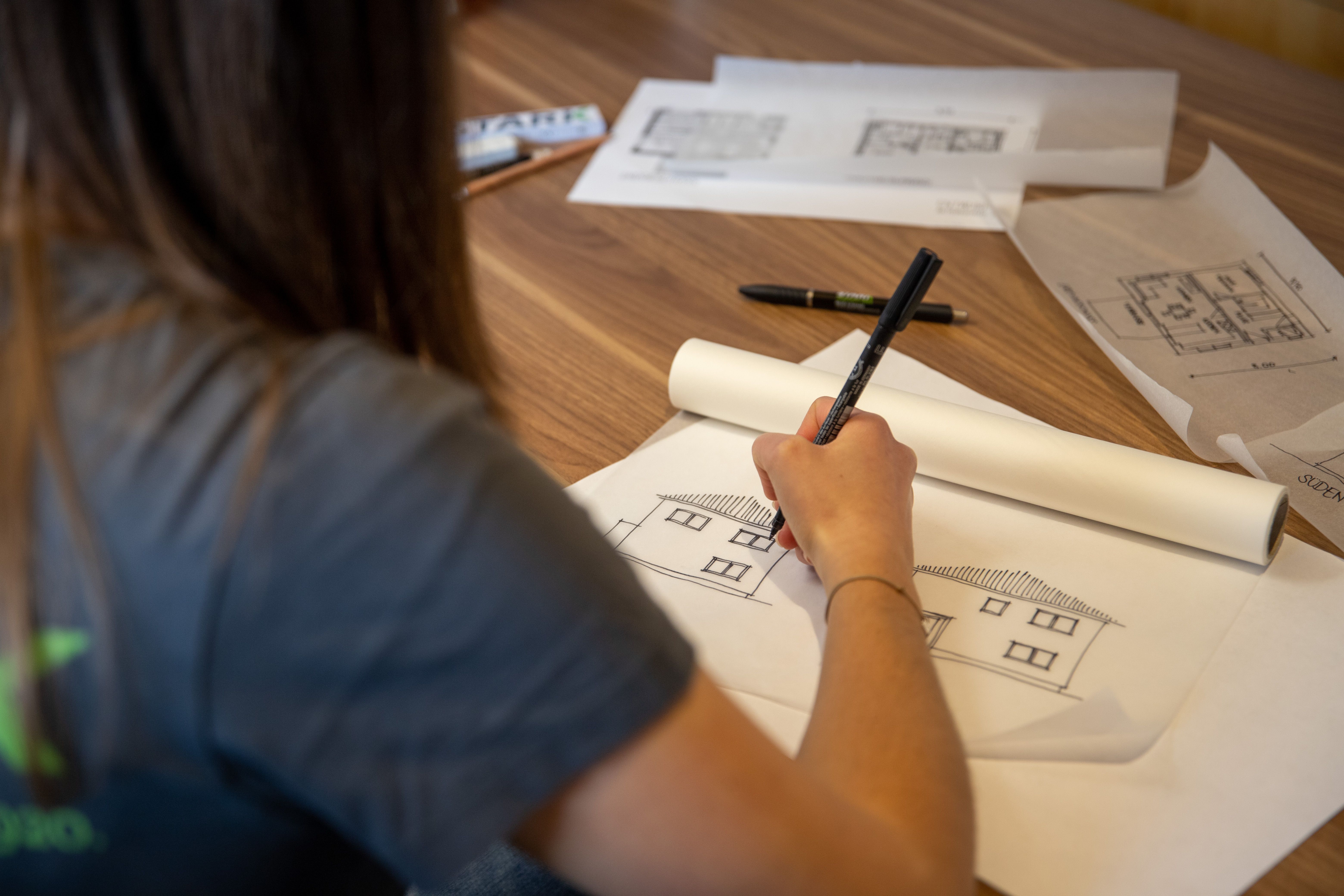 Bautechnikerin zeichnet eine Fassadenansicht mit Fineliner