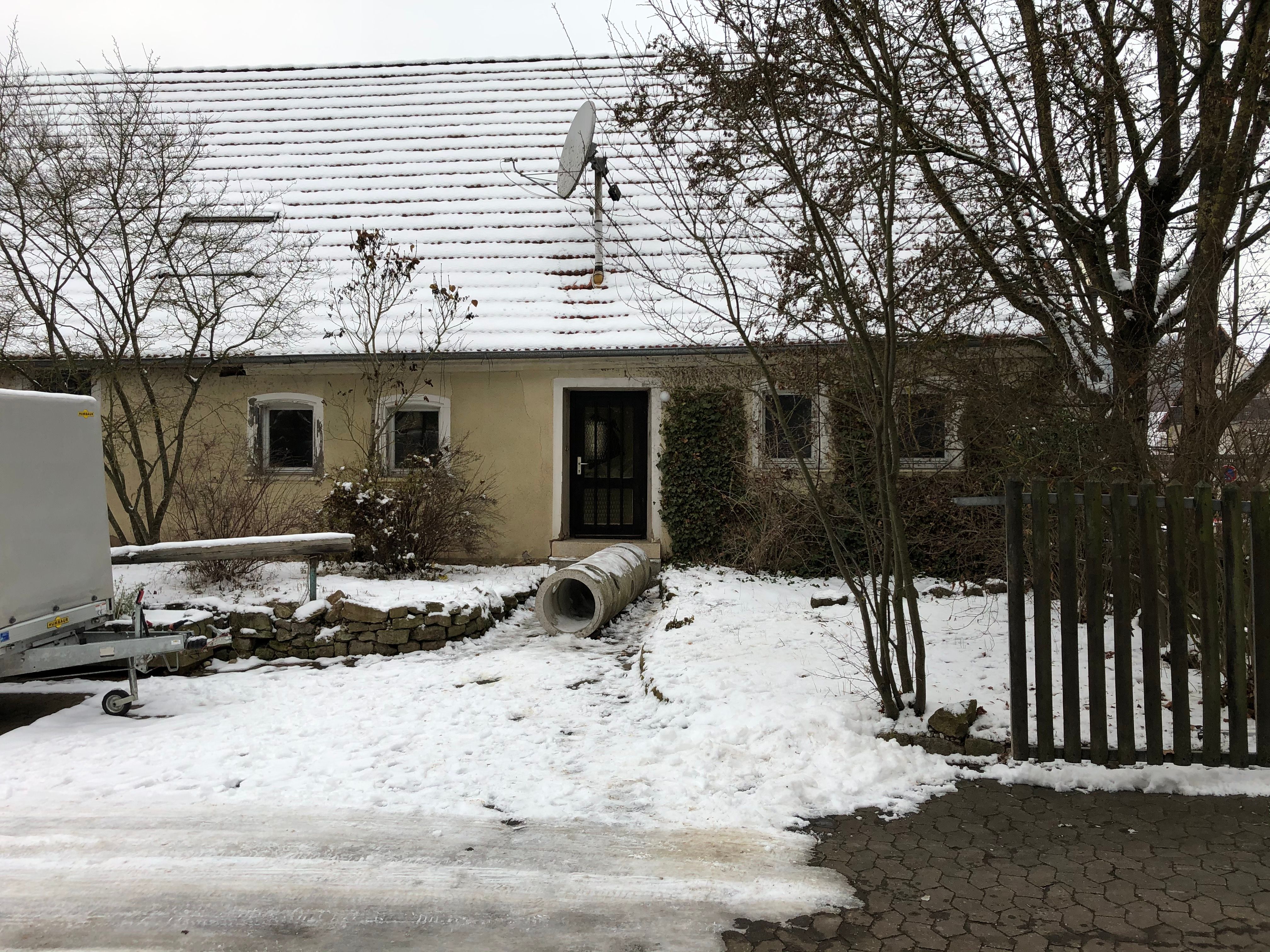 Unsaniertes Wohnhaus mit verwittertem Putz im Schnee