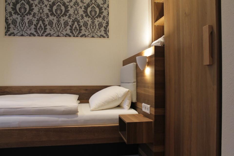 Hotel Feuchtwangen — Hotelzimmer mit Holz-Kopfteil, Wandleuchten, gemütliche Atmosphäre
