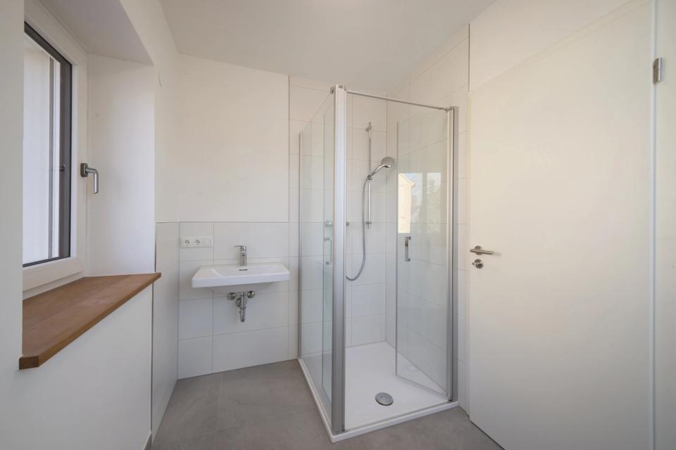 Dachbad mit Eckdusche, Waschbecken und Holzfensterbank