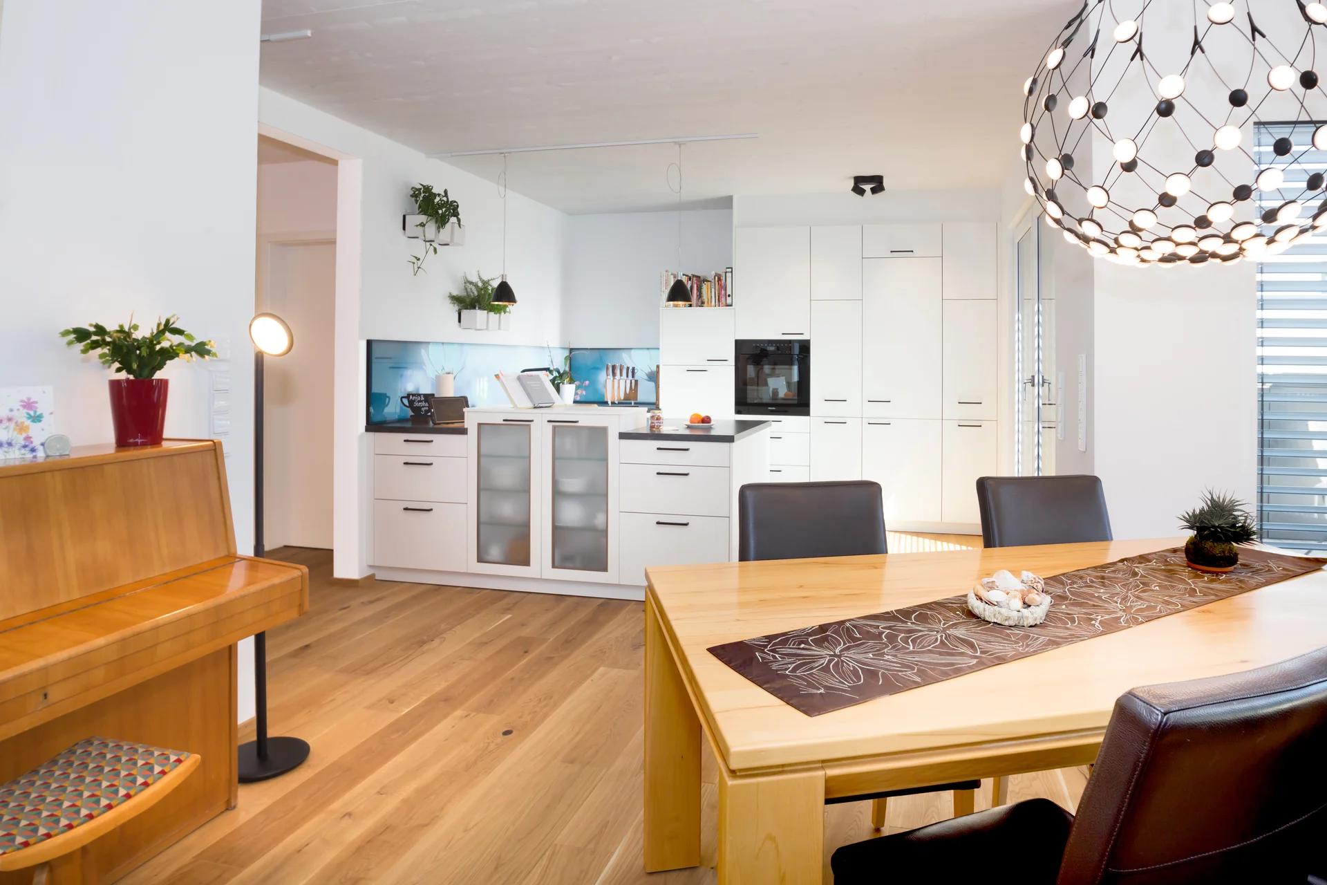 Essbereich mit Holztisch und Designerlampe, Küche im Hintergrund — Zimmerei Stark