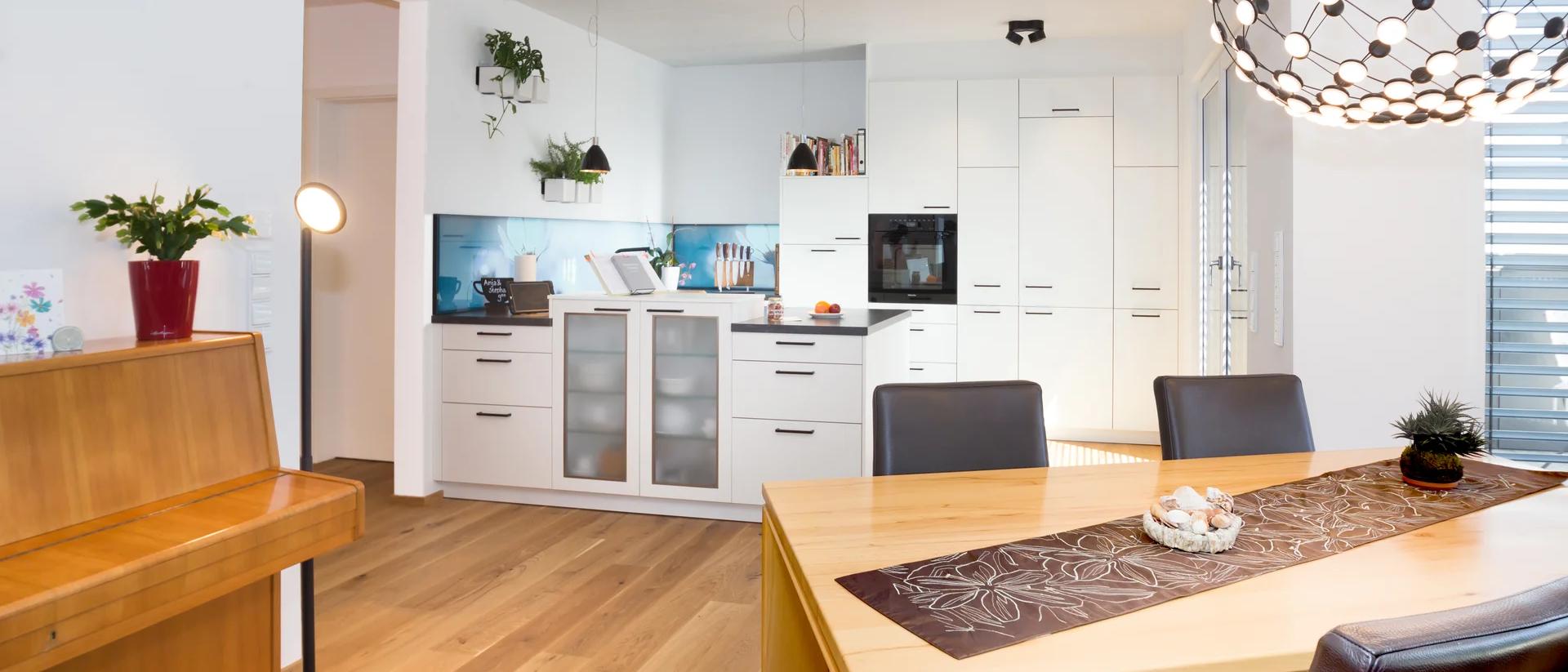 Essbereich mit Holztisch und Designerlampe, Küche im Hintergrund — Zimmerei Stark