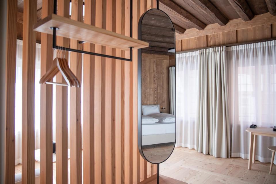 Hotelzimmer im Altbau mit Holzlamellenwand, Spiegel und alter Balkendecke