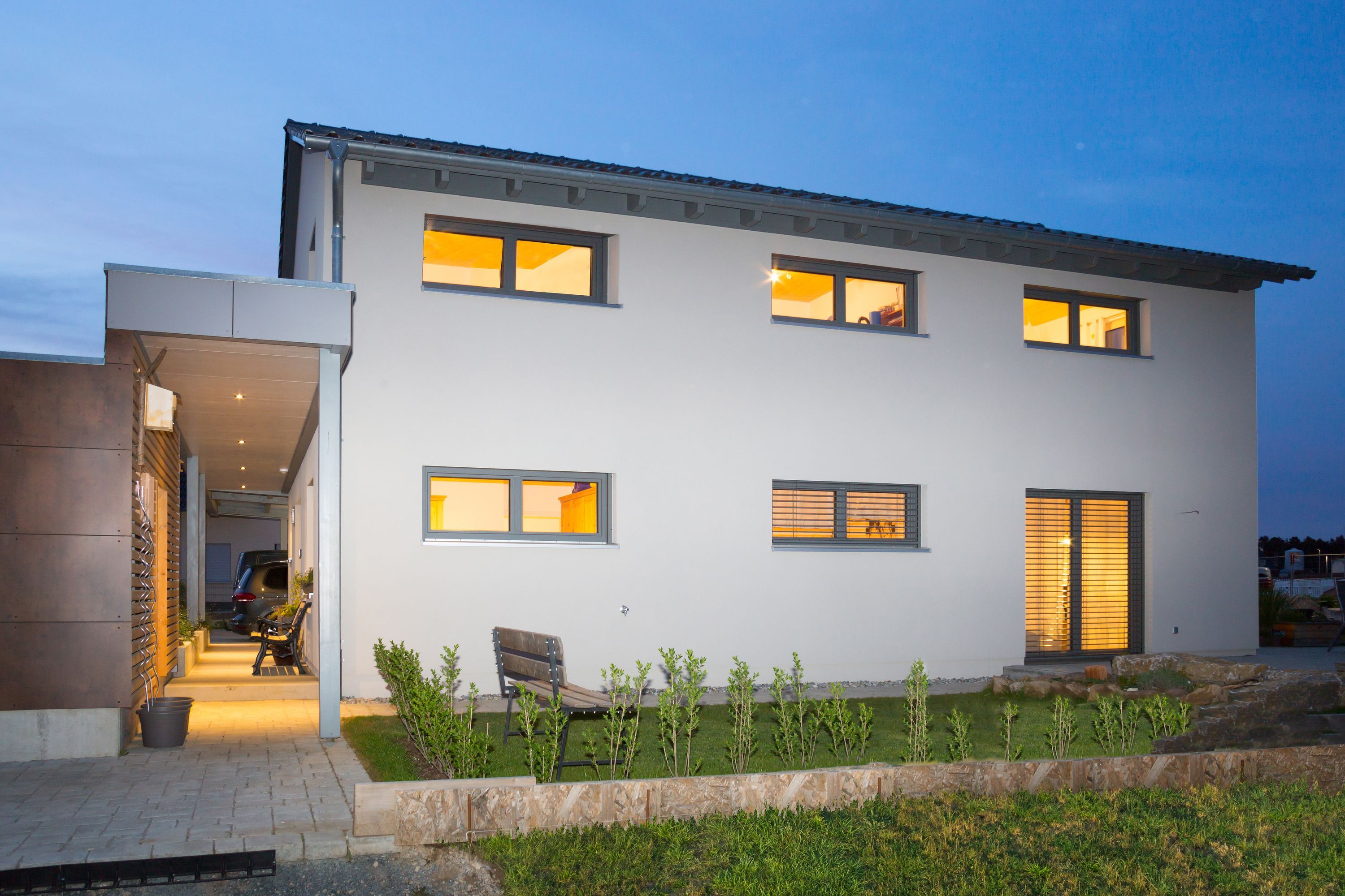 Hausseite mit beleuchteten Fenstern in der Abenddämmerung