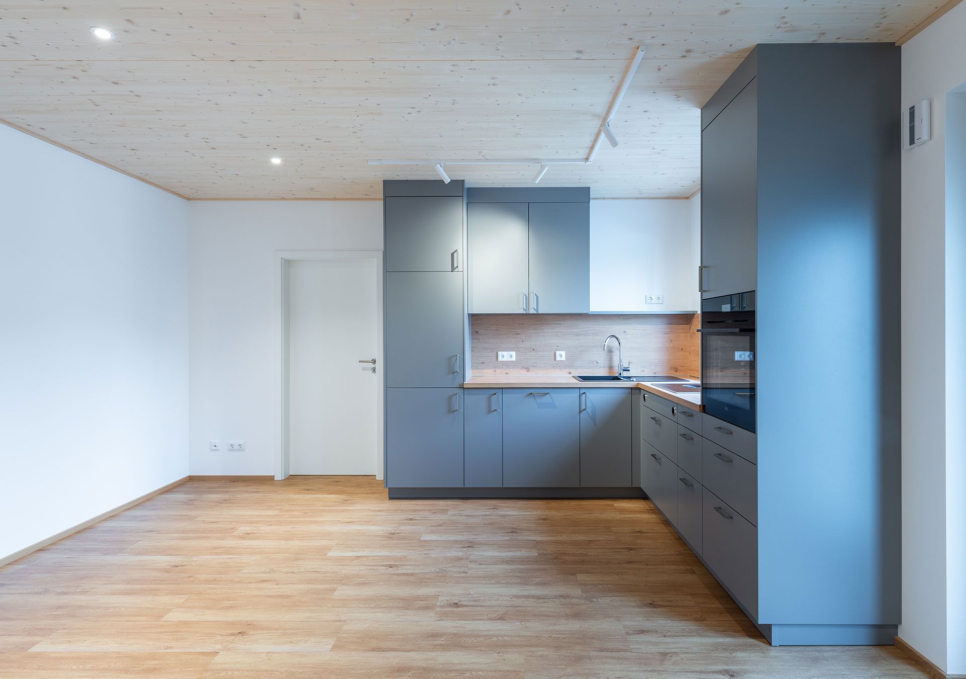 Offene Küche mit grauen Fronten, Holzdecke und Eichenboden
