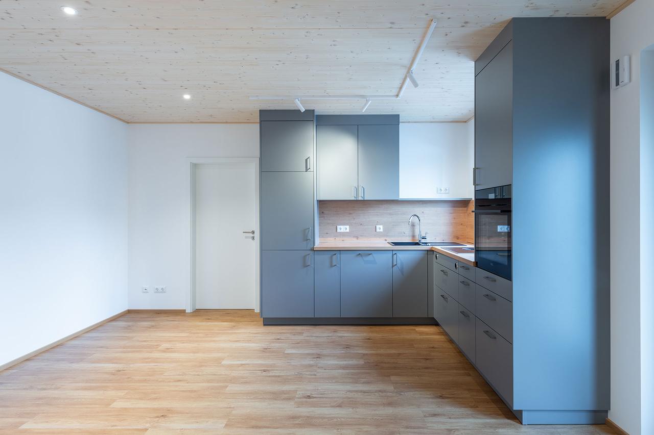 Offene Küche mit grauen Fronten, Holzdecke und Eichenboden