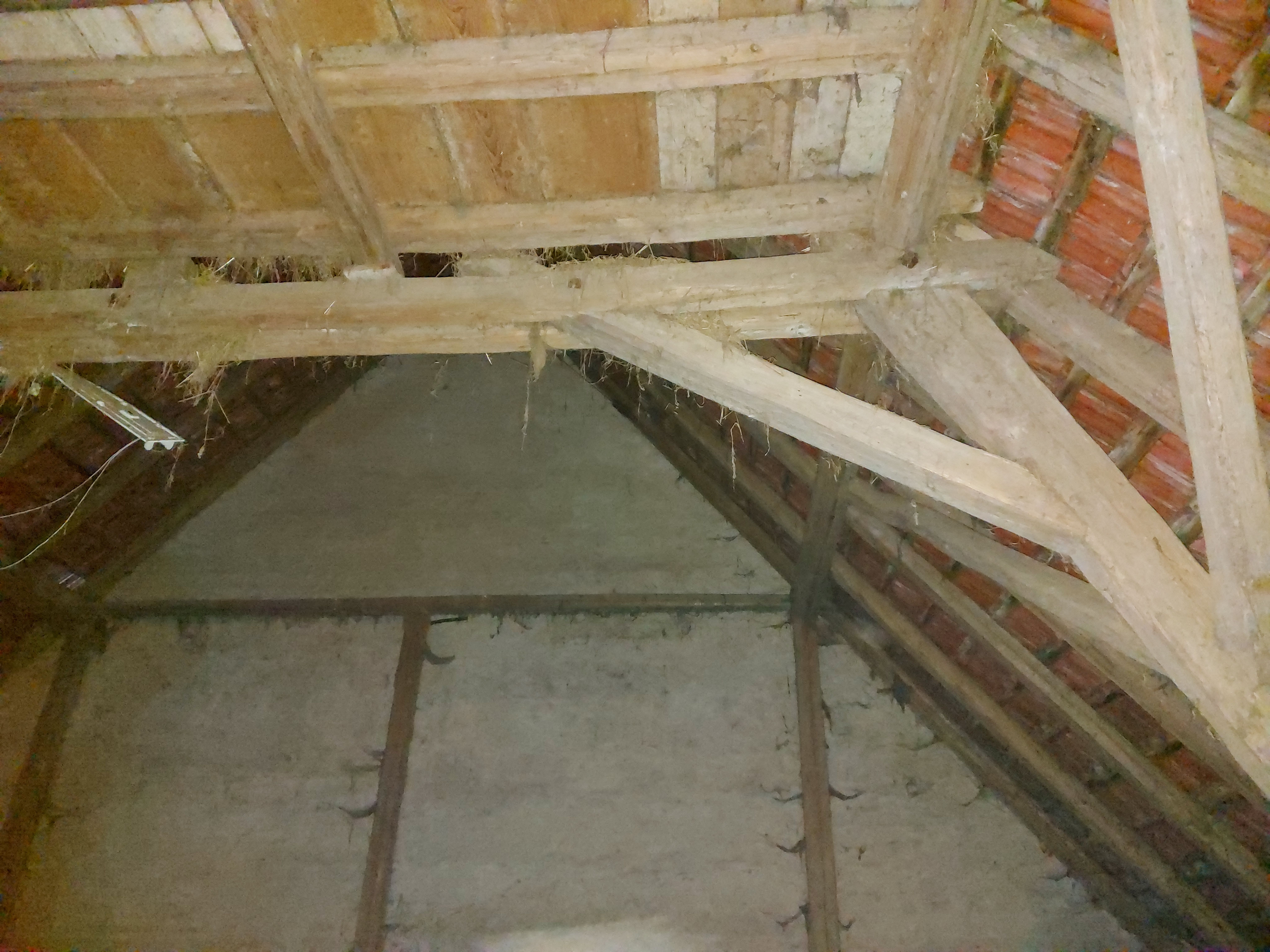 Alter Dachstuhl mit Holzbalken und Ziegeln vor der Sanierung