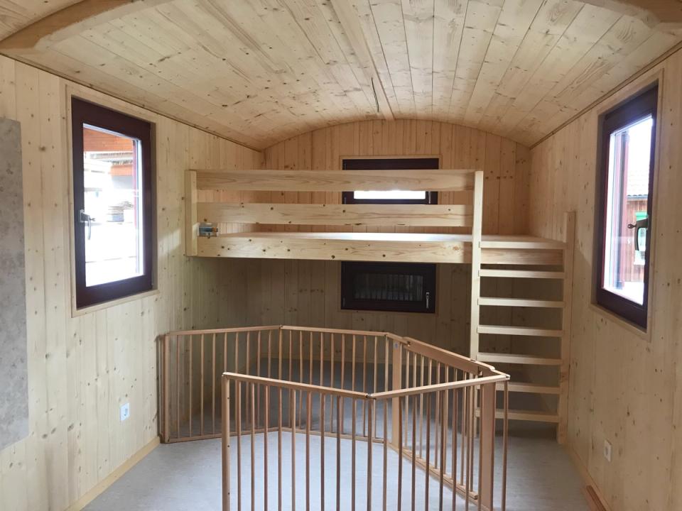 Hochebene mit Treppe im Waldkindergartenwagen, davor ein Schutzgitter aus Holz