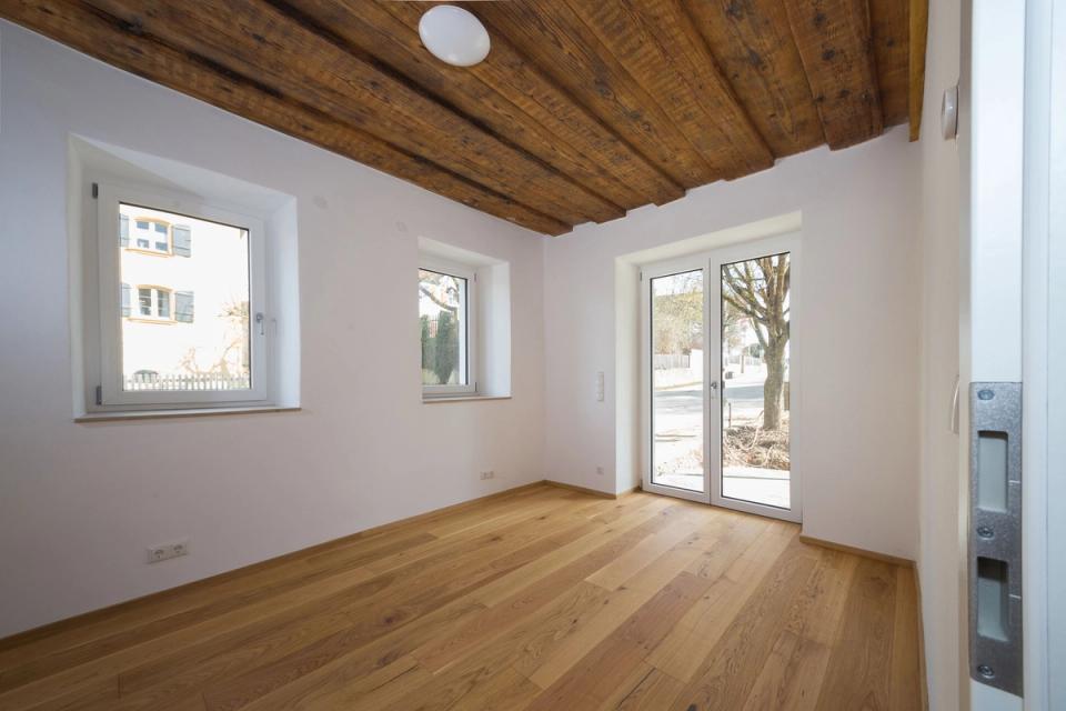 Zimmer mit sichtbarer Holzbalkendecke, Parkett und Terrassentür