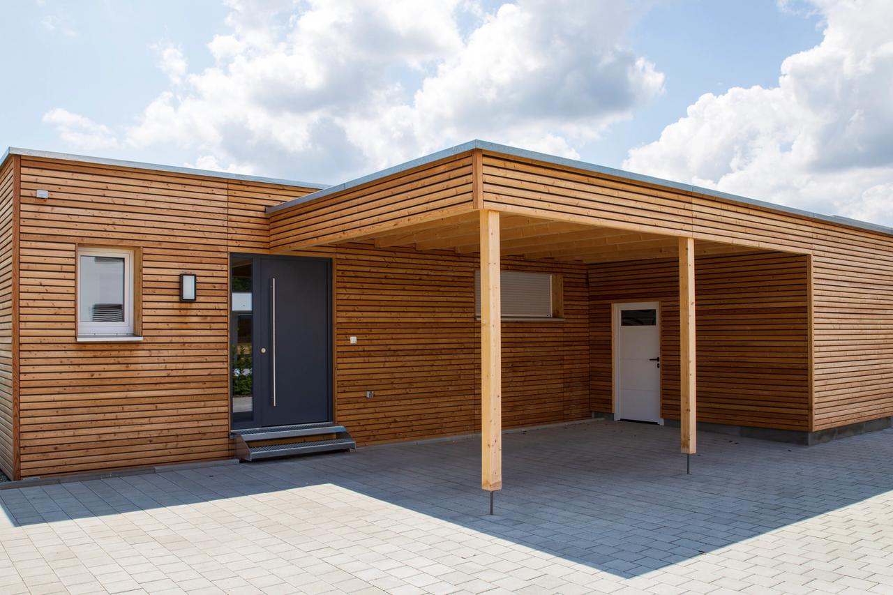 Hauseingang mit dunkler Haustür und überdachtem Carport aus Lärchenholz