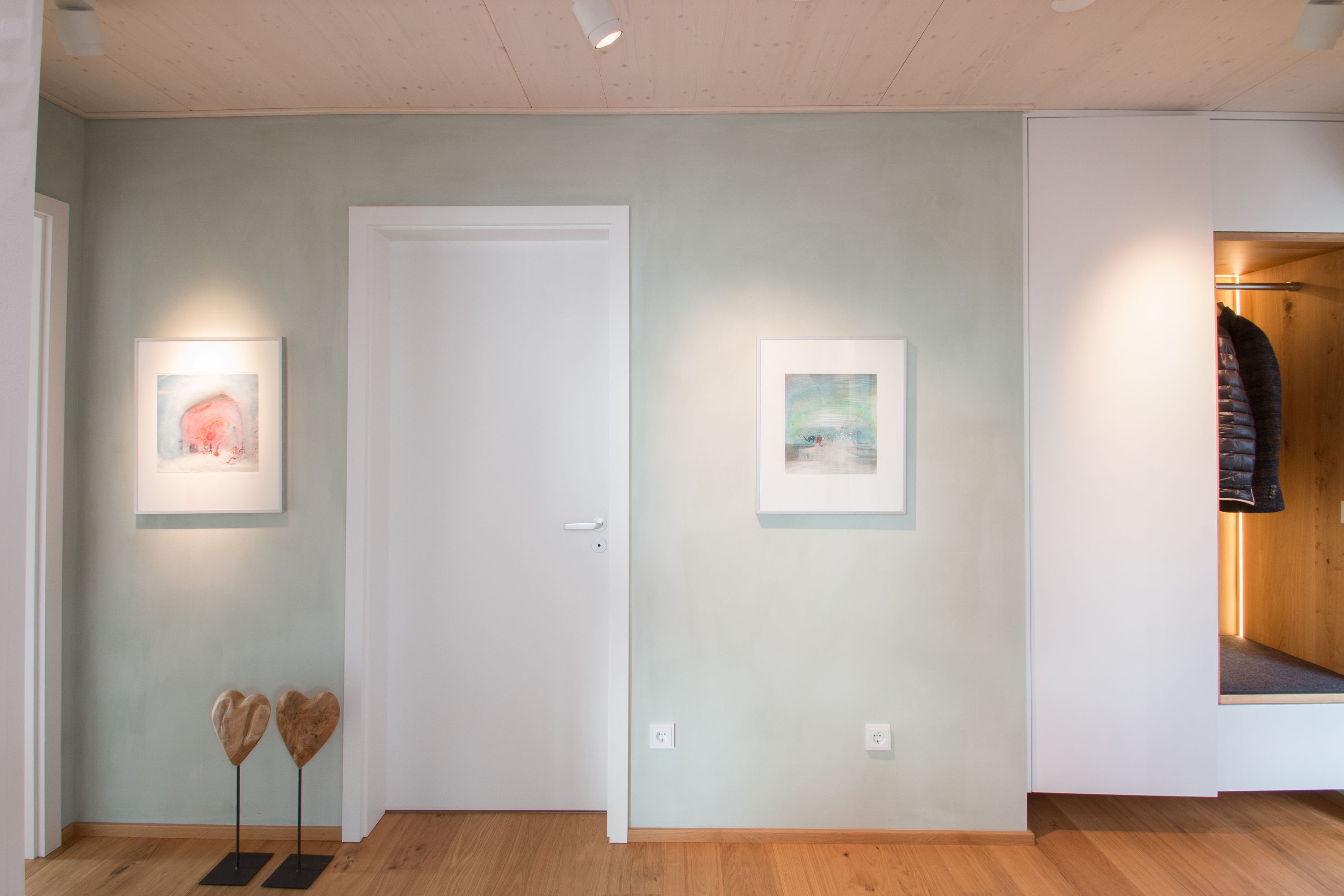 Diele mit salbeigrüner Lehmputzwand und beleuchteter Garderobe